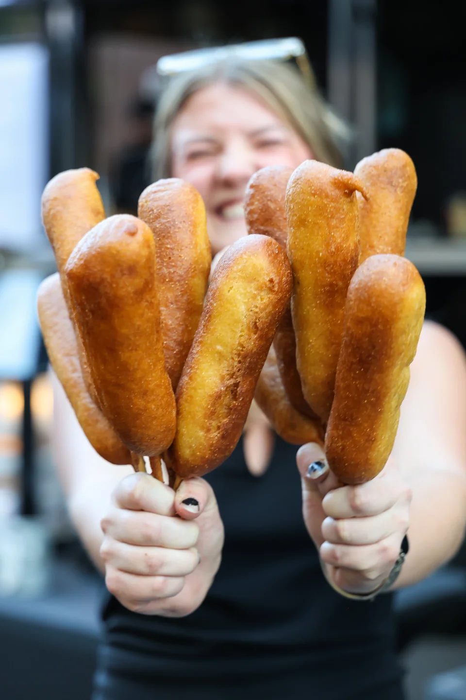 Woman holding a bouquet of corndogs on sticks outside The Gravy Train