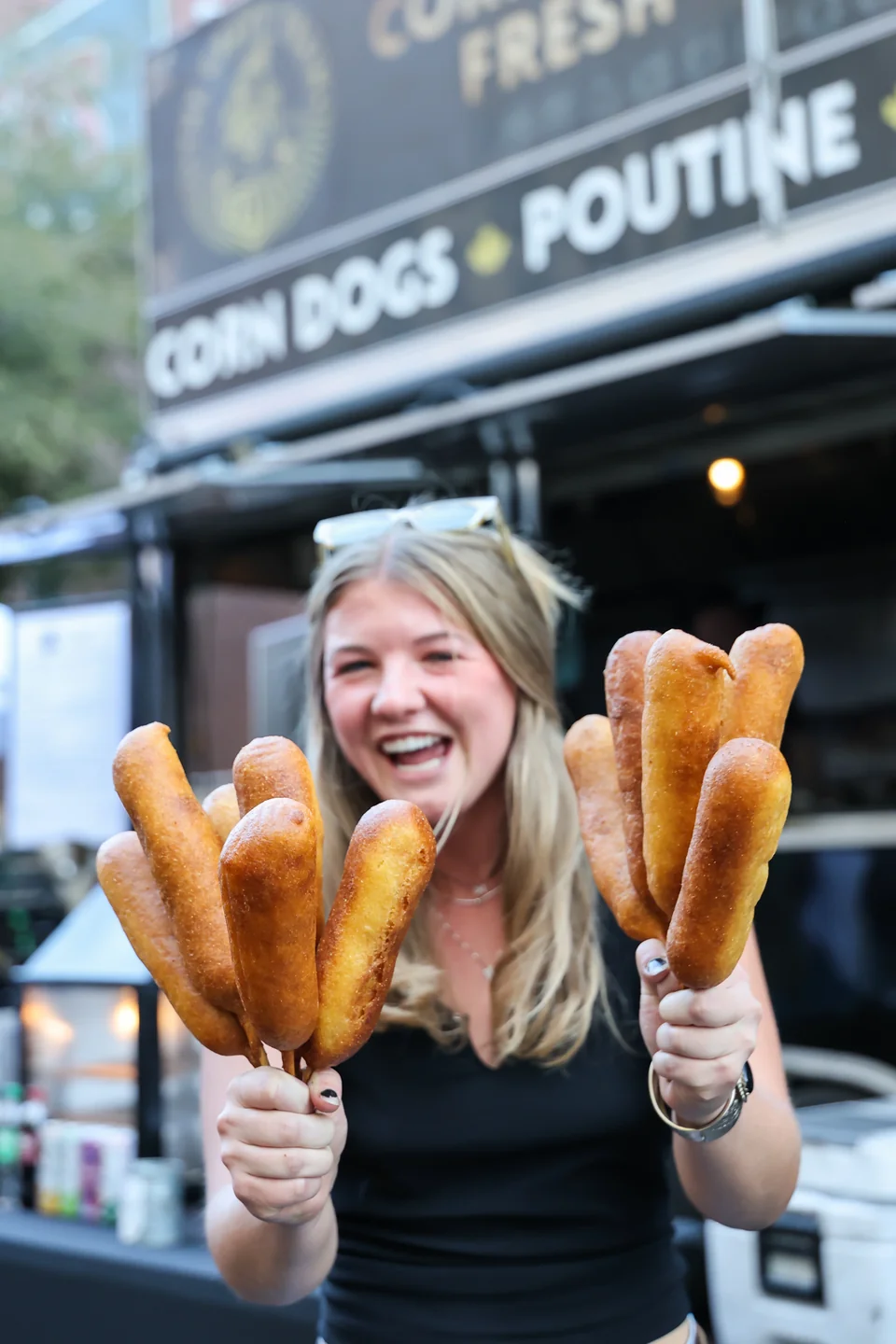 Woman with corndogs in front of The Gravy Train truck, cowboy boots