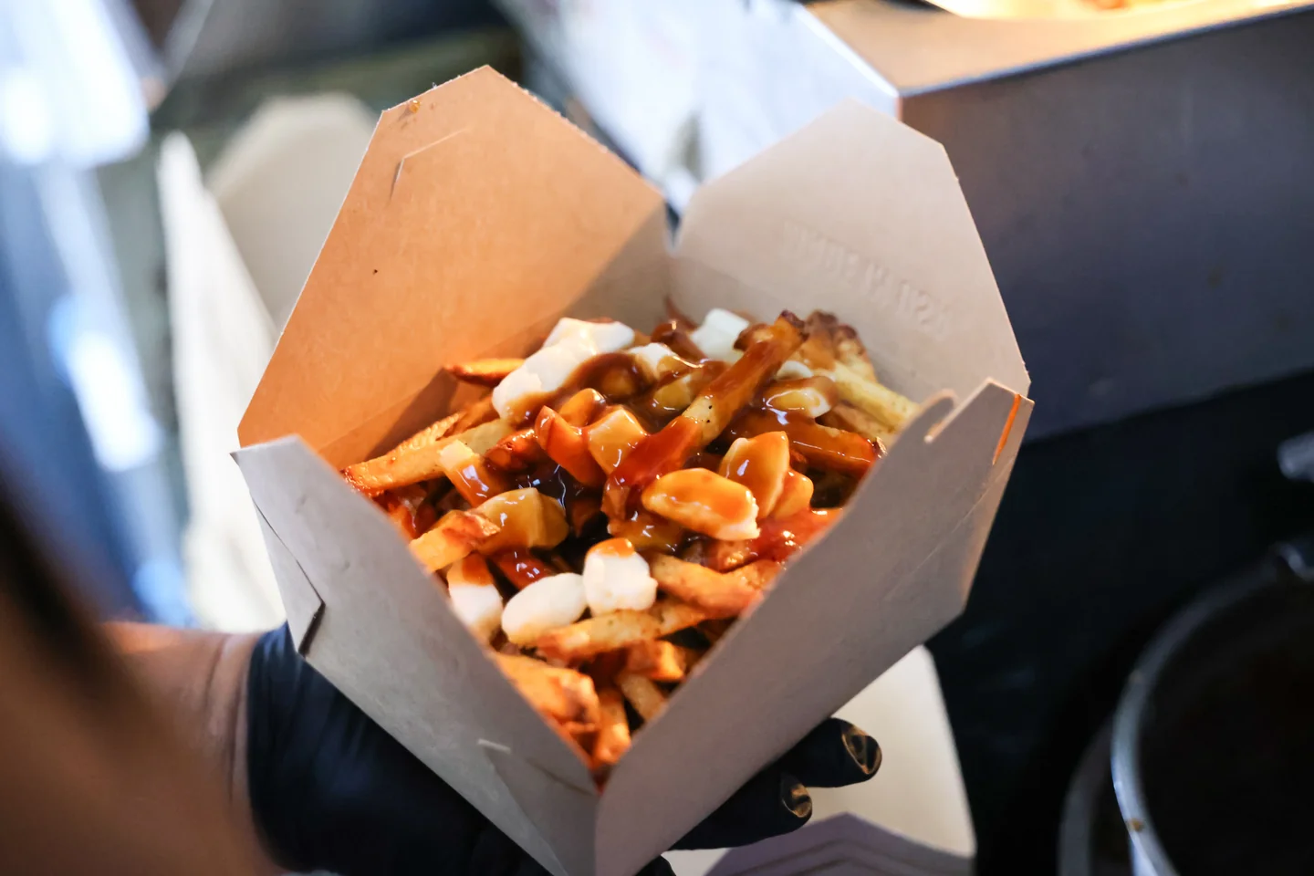 Poutine with gravy poured over fries and cheese curds in a kraft box